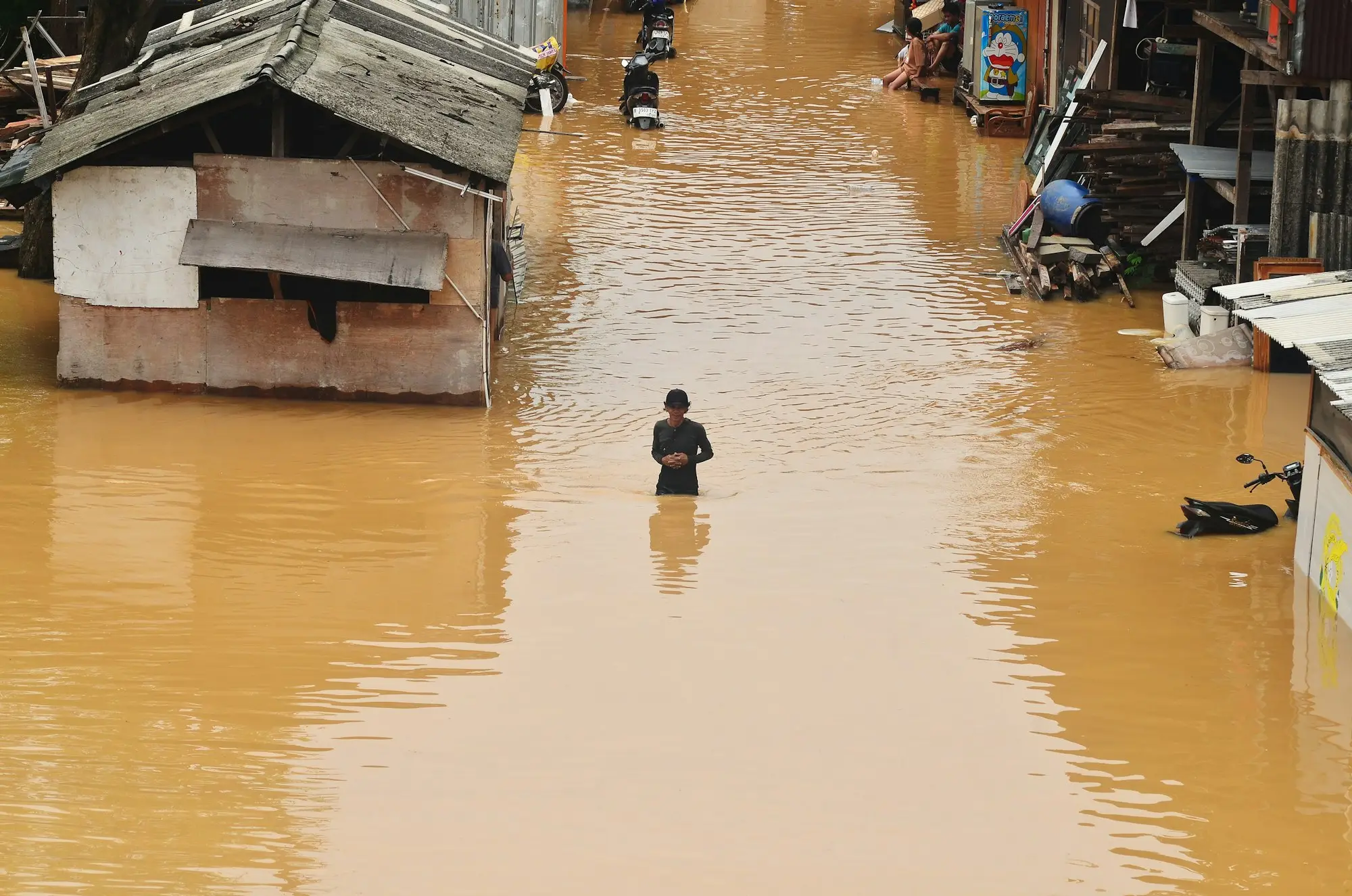 Shop owner cleaning up mud and water damage inside a flooded shopfront